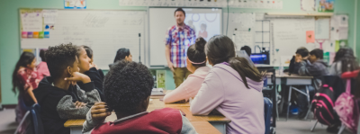 A group of young adults sat in a classroom listening to their teacher