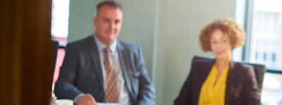 A man and a woman in professional attire sat behind a desk