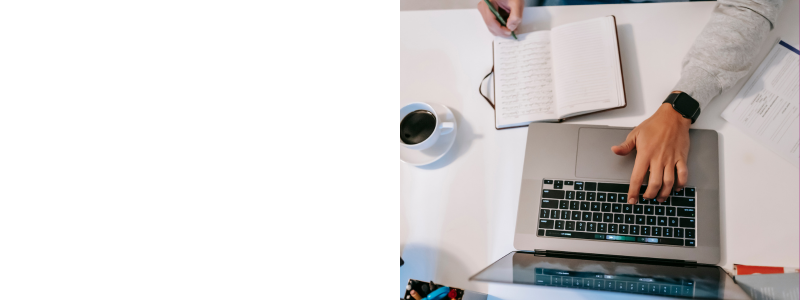 hands typing on a laptop keyboard with an open notebook